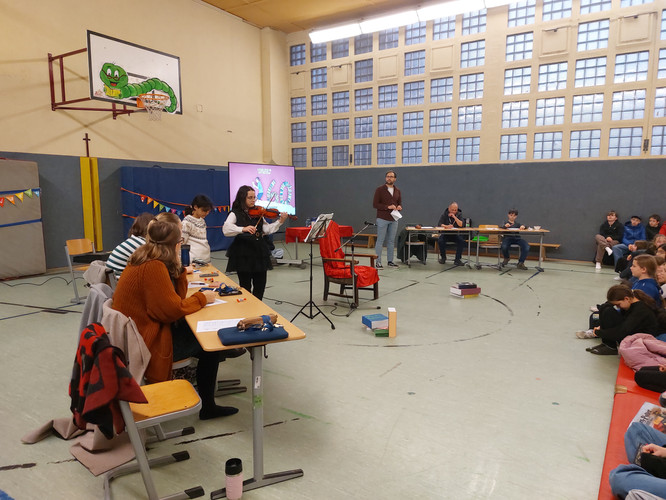 KI generiert: In einer Turnhalle findet eine Veranstaltung statt, bei der eine Person vor einem Publikum Geige spielt. Mehrere Personen sitzen an Tischen und es scheint eine Art Präsentation oder Wettbewerb zu sein.