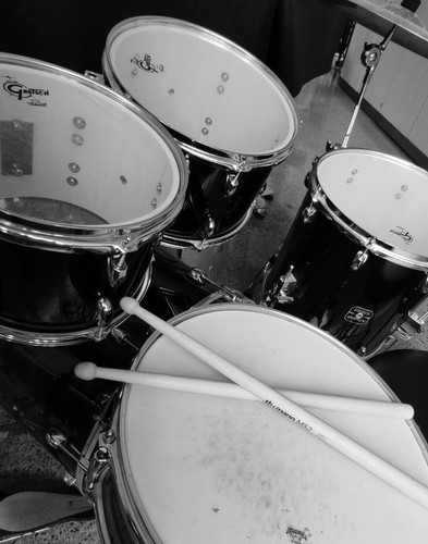 KI generiert: Das Bild zeigt ein Schlagzeug-Set mit Trommeln und Drumsticks, die auf der Snare-Drum liegen. Es ist in Schwarz-Weiß gehalten und der Fokus liegt auf den Details der Schlaginstrumente.