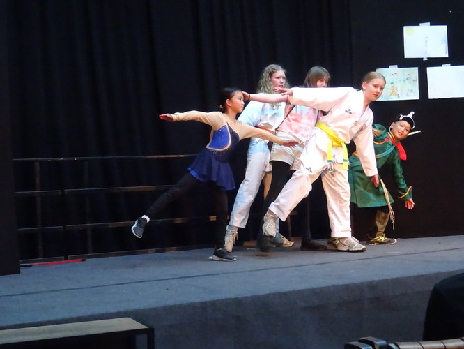 KI generiert: Das Bild zeigt fünf Kinder in unterschiedlichen Kostümen, die auf einer Bühne in einer Pose stehen. Sie scheinen an einer Theateraufführung oder einem Schulprojekt teilzunehmen.